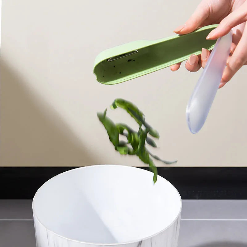 Dark green vegetable peeler with stainless steel blade stored inside a transparent plastic tube.