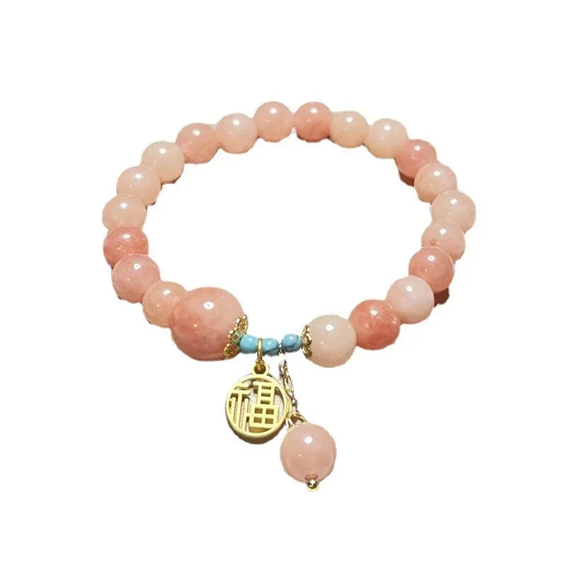 A simple pink natural stone and alloy bracelet with an adjustable clasp on a wrist.