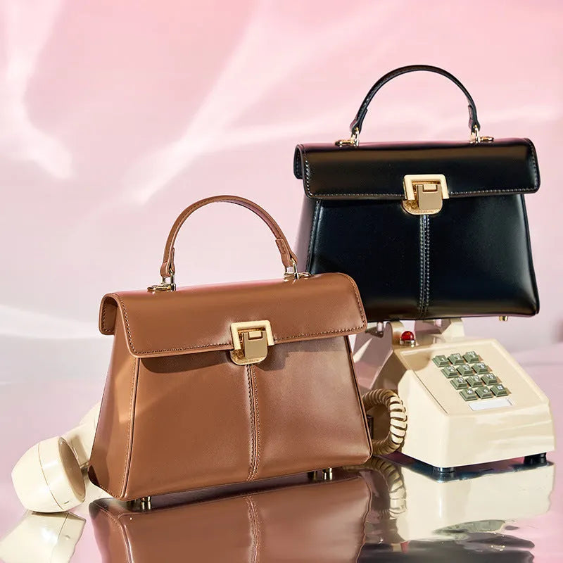 Women's black leather shoulder bag with a vachette clasp, showing its horizontal square shape and adjustable strap.