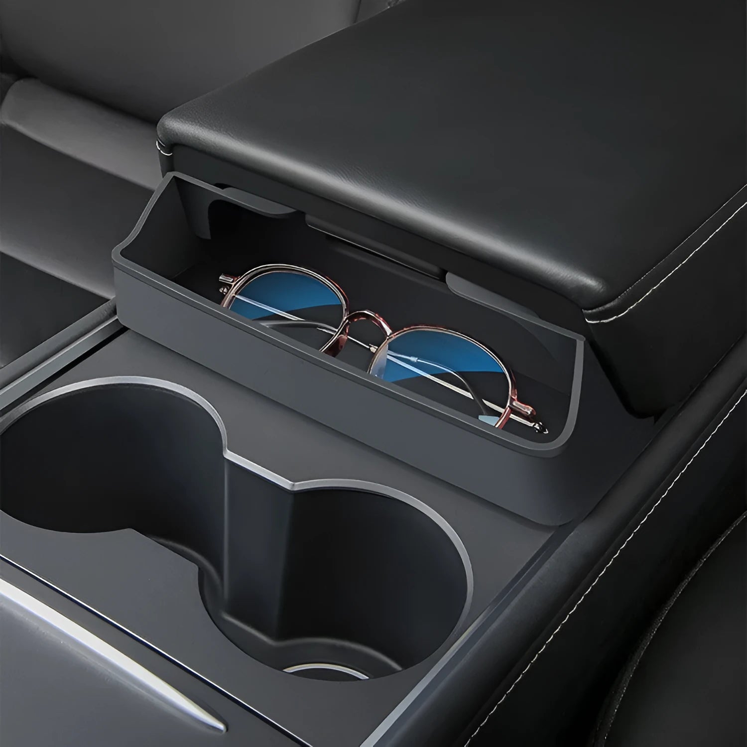 Black silicone sunglasses case mounted in a Tesla Model 3 or Y centre console.
