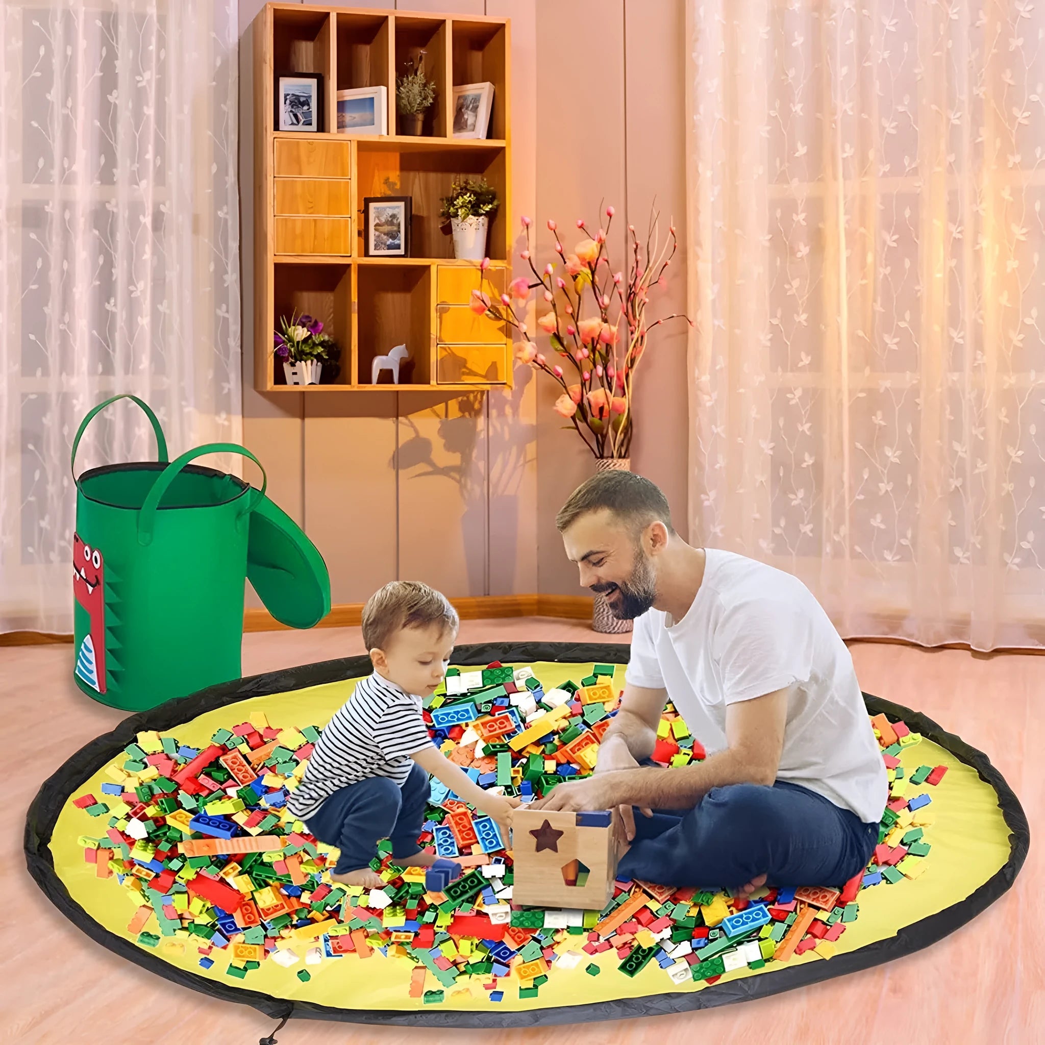 Green felt cube-shaped toy storage bag opened flat as a play mat next to toys, showing pull rope.
