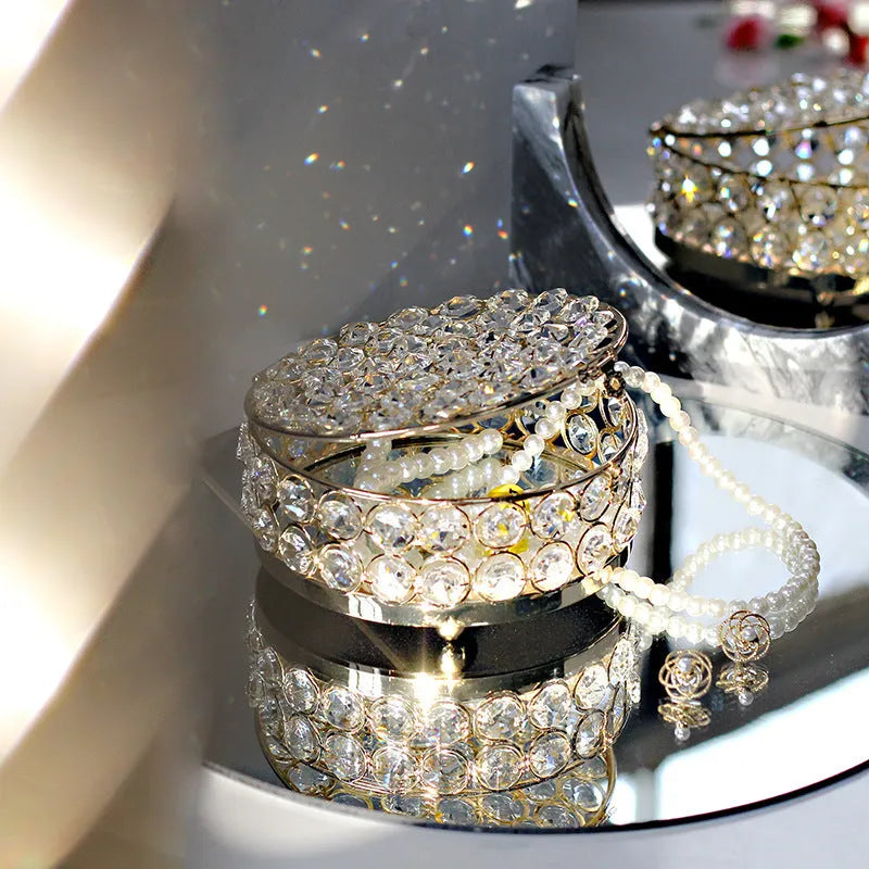 French gold metal jewelry box with a clear crystal glass lid and a lock, shown on a surface.