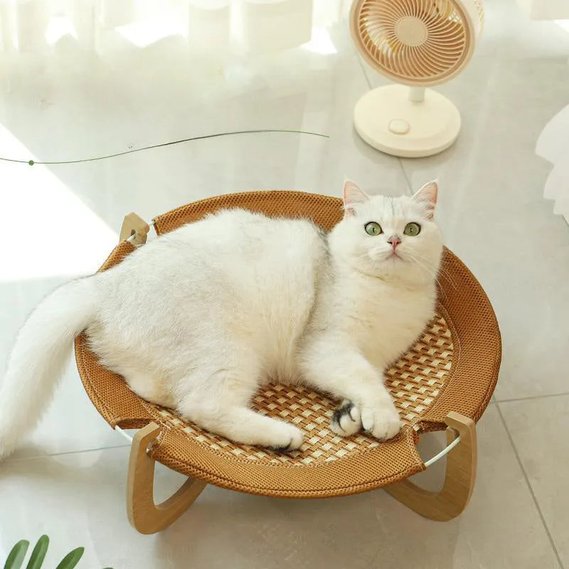 Brown woven rattan elevated hammock bed for cats and small dogs on a wooden floor.
