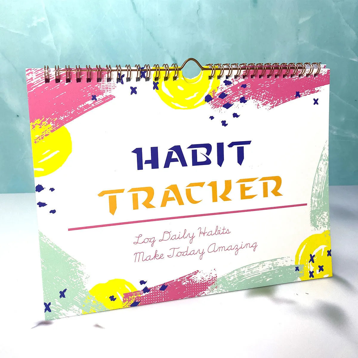 A5 habit tracking notebook in open position showing internal pages, with a choice of pink, purple, floral, or yellow and white covers.