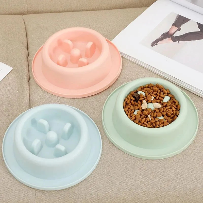 Blue pet slow feeder bowl with raised obstacles on a kitchen floor.