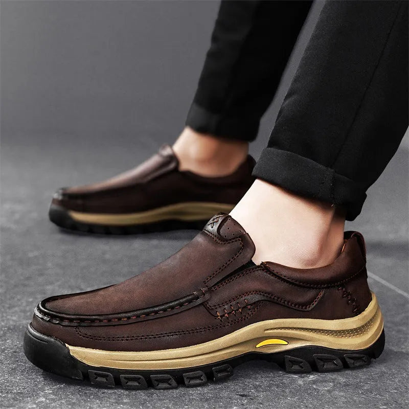 Men's black leather hiking shoes with thick rubber soles and round toe on a rocky outdoor path.