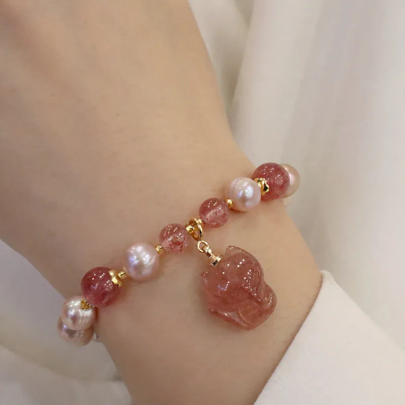 Women's light pink freshwater pearl bracelet with strawberry quartz beads and a small fox charm on an adjustable cord.