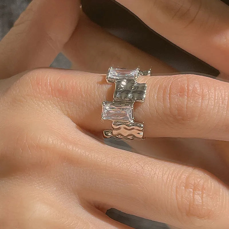 Silver geometric cross ring with open zircon stone setting.