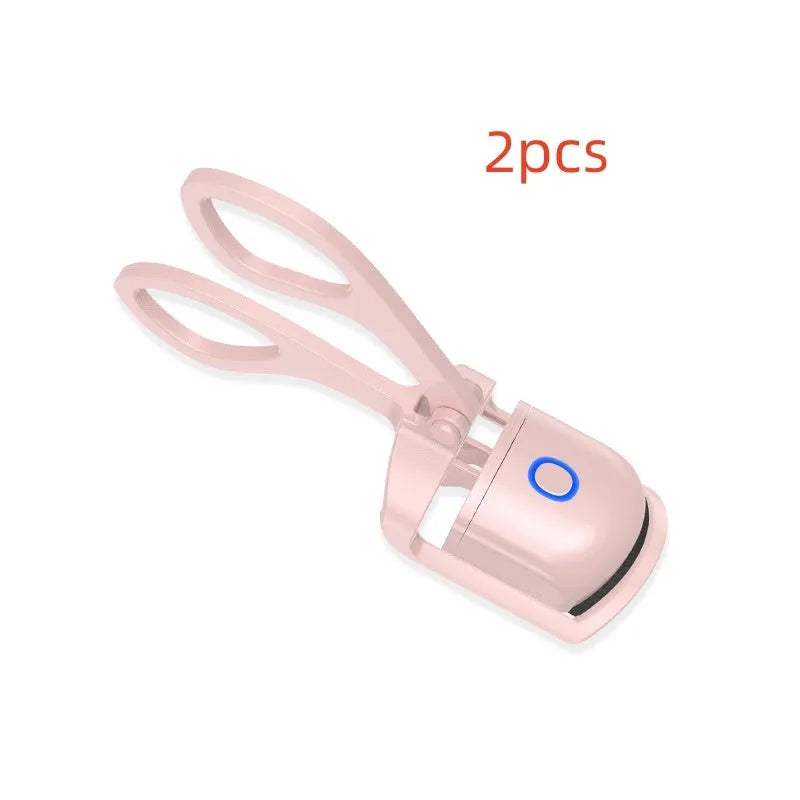 White USB rechargeable heated eyelash curler with dual temperature lights, shown next to its charging cable.
