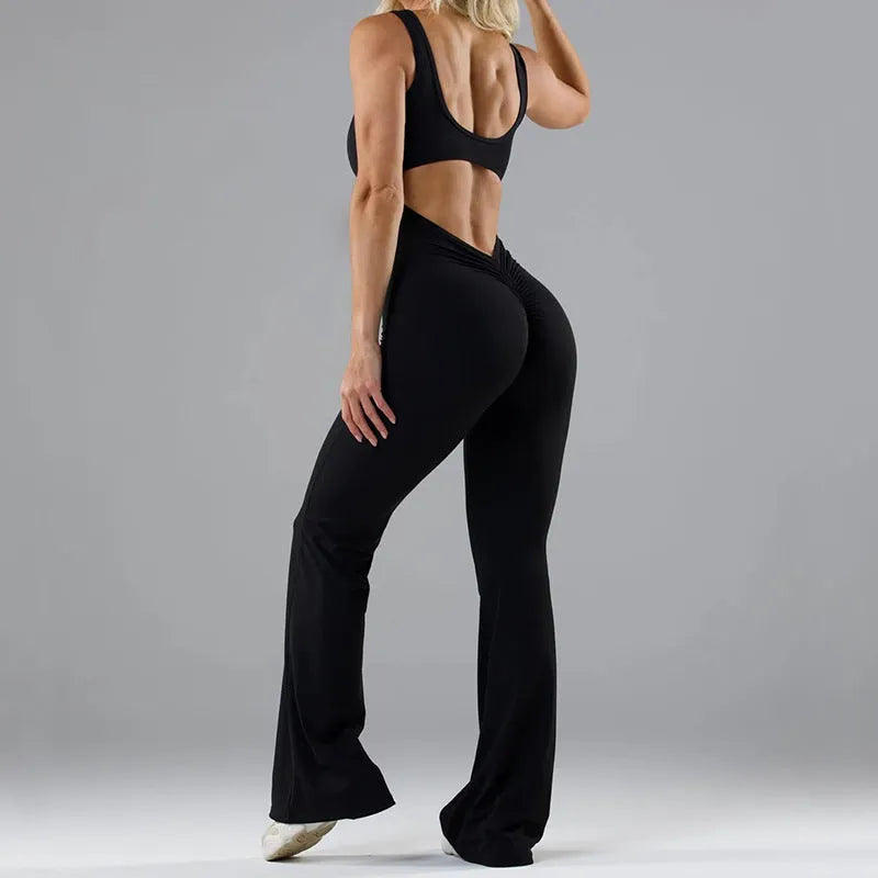 Black seamless women's yoga bodysuit jumpsuit with built-in chest pad, shown on model.