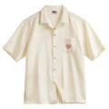 Light apricot men's shirt with bamboo and flower pattern, Cuban collar, on a hanger.