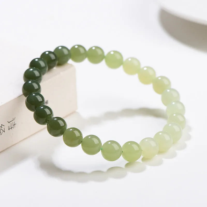 Natural clear water Hetian jade bracelet showing gradient colour on round beads and barrel beads.