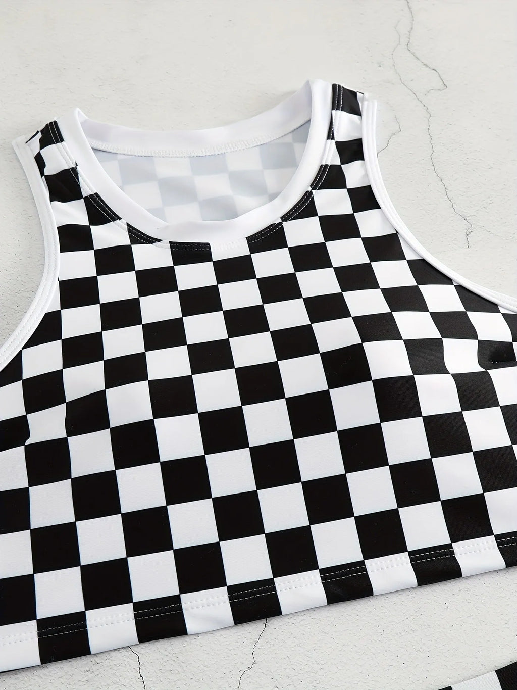 Women's black and white plaid racing one-piece swimsuit with backless design and adjustable suspender straps.