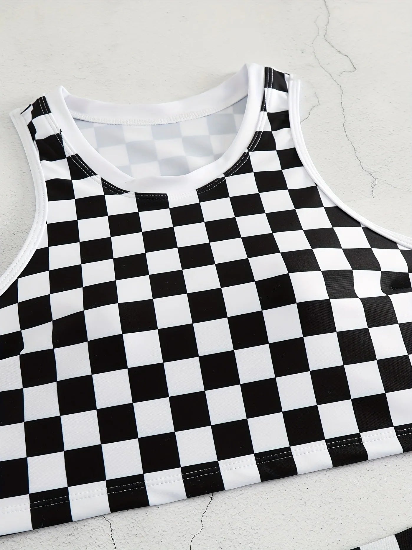Women's black and white plaid racing one-piece swimsuit with backless design and adjustable suspender straps.