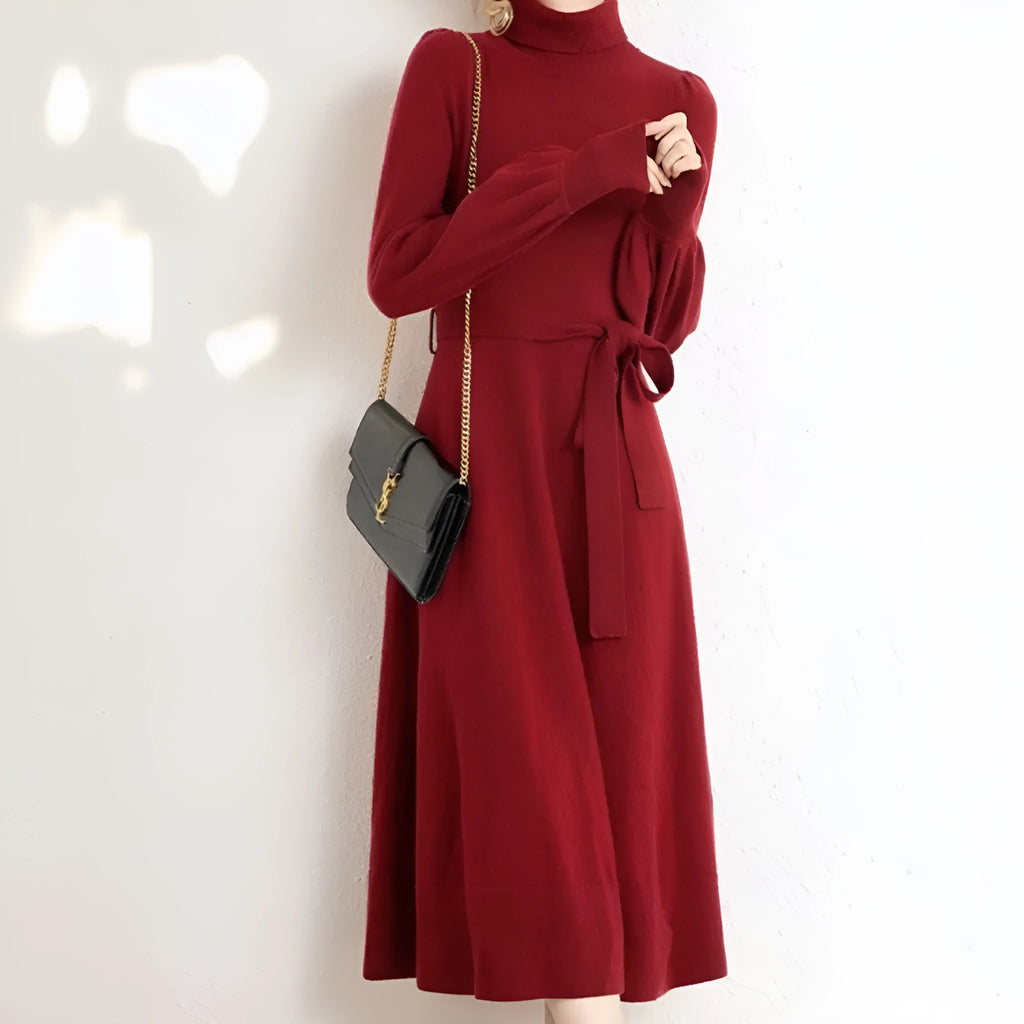 A woman wearing a rose red knitted turtleneck dress with a loose midi skirt and long sleeves.