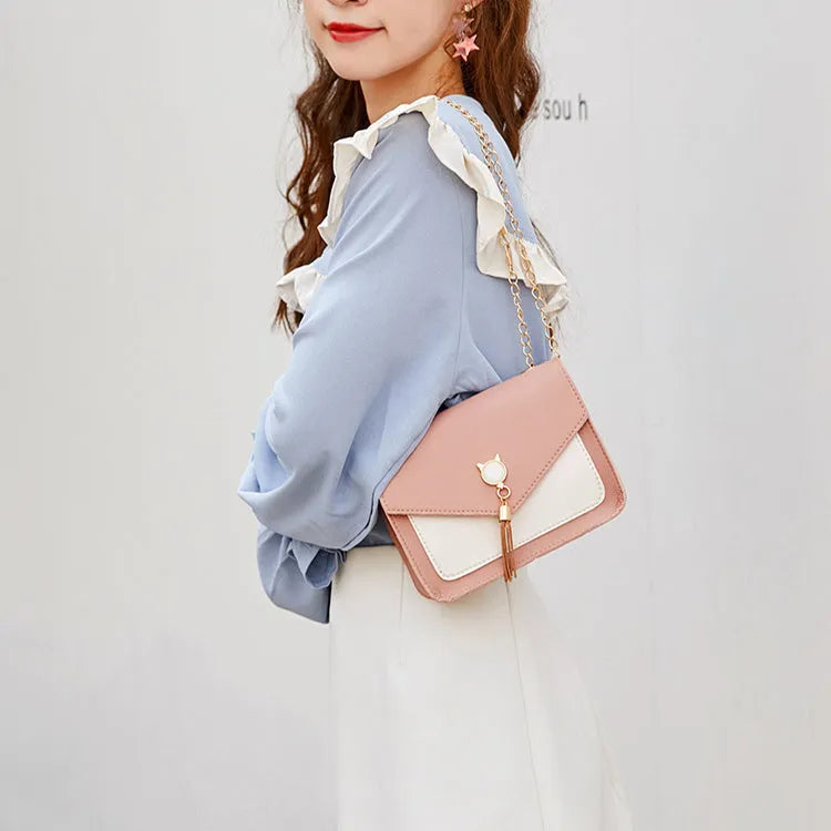 Small square PU leather crossbody bag with cat tassel decoration, magnetic flap, and adjustable chain strap in black