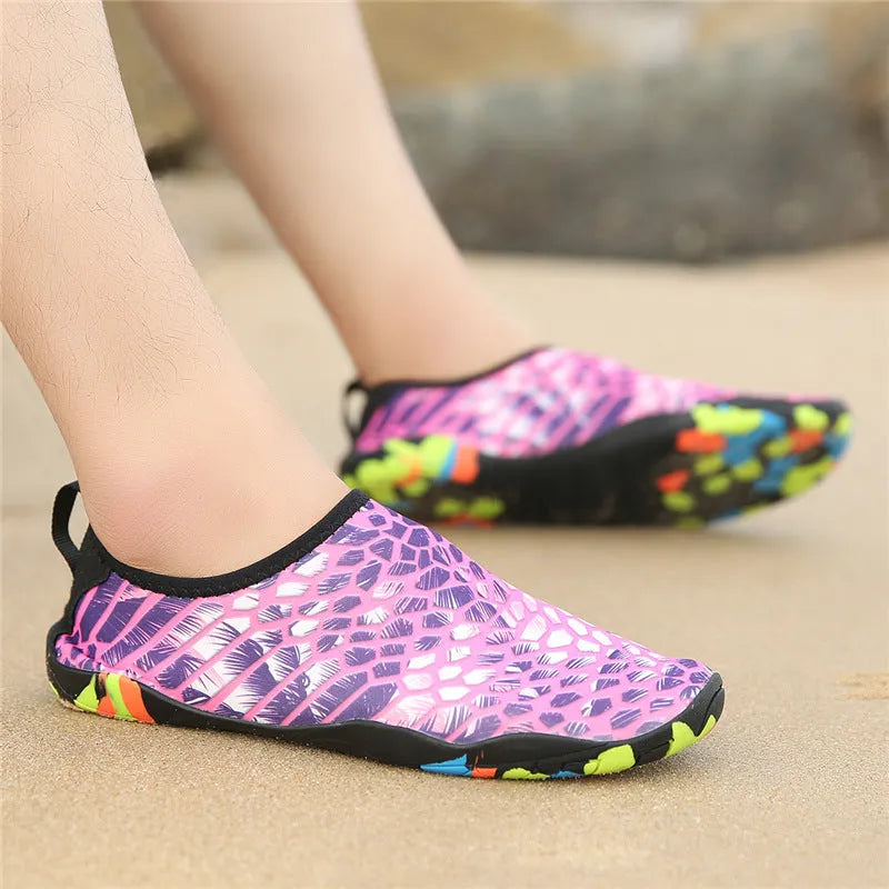 Blue Lycra beach wading shoes for men and women on a sandy shore.