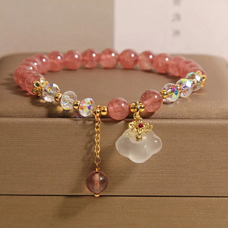 Women's bracelet with strawberry quartz and white agate beads and metal auspicious cloud charms on a white background.
