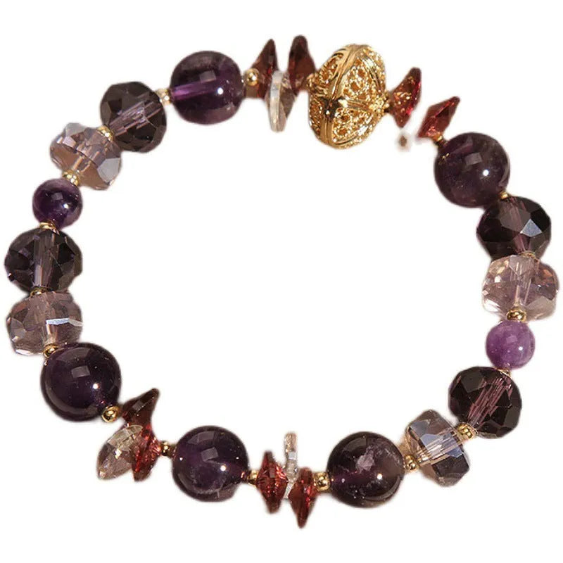 Purple crystal bracelet with pumpkin beads and a wind chimes charm on wrist.