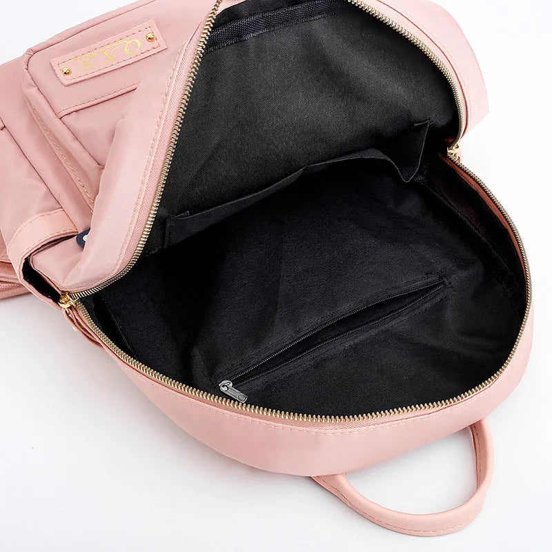 Black and pink views of a women's casual nylon backpack with double straps, a soft handle, and an external pocket.