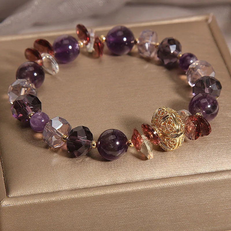 Purple crystal bracelet with pumpkin beads and a wind chimes charm on wrist.