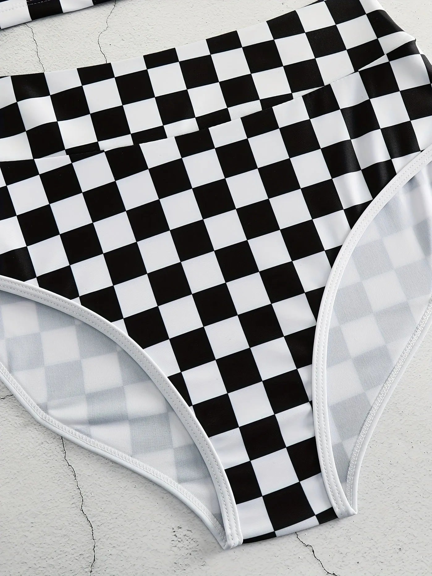 Women's black and white plaid racing one-piece swimsuit with backless design and adjustable suspender straps.