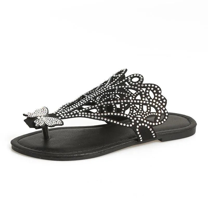 Women's black slip-on sandals with rhinestone decoration and a flip-toe design on a flat rubber sole.