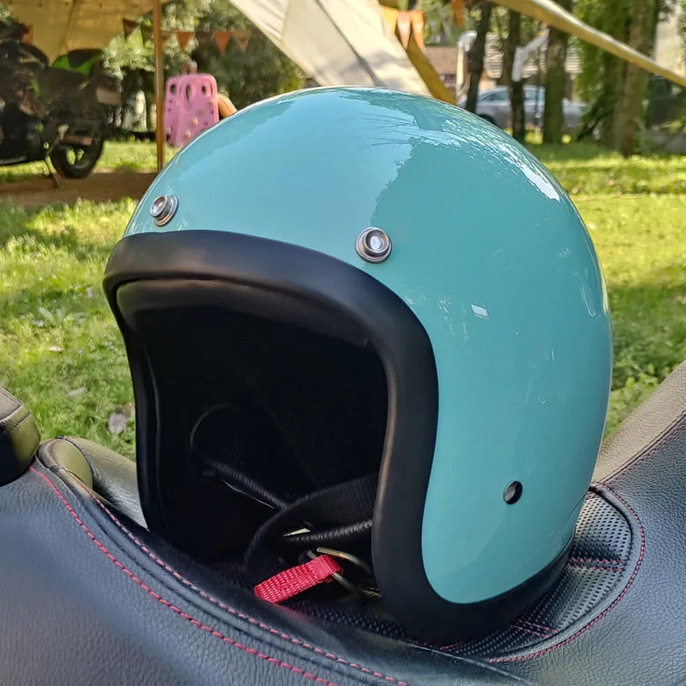 Retro-style open face motorcycle helmet in fibreglass, shown in a selection of colours including cement grey and matte black.
