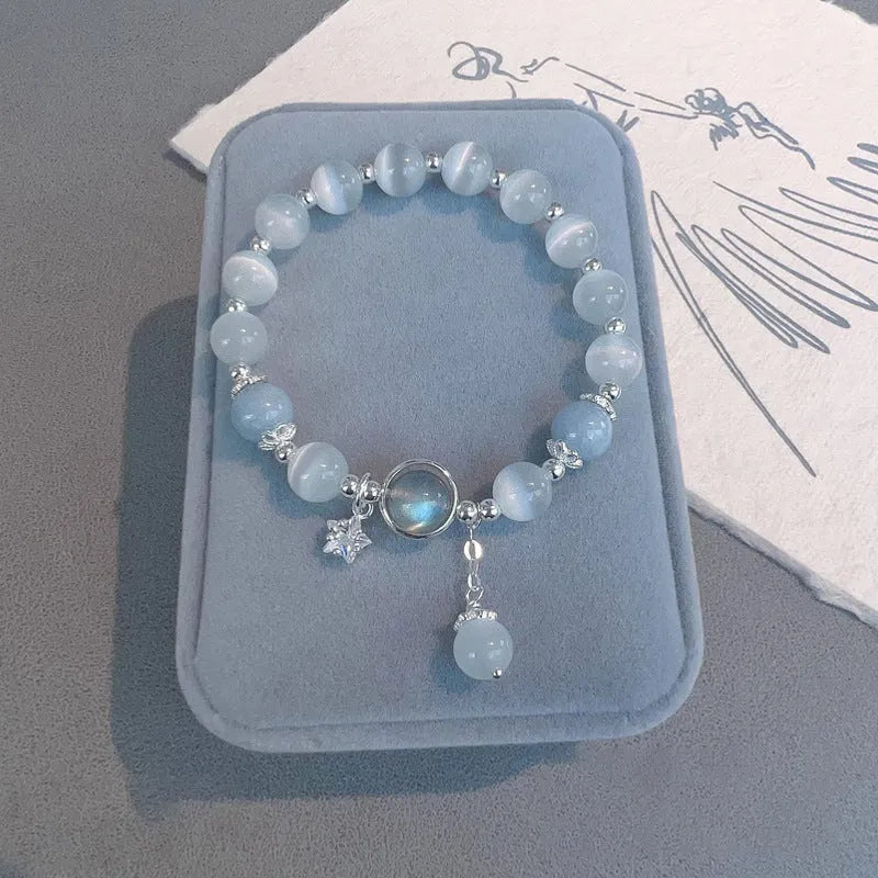 Women's opal cat's eye stone bracelet with diamond-shaped beads on wrist.