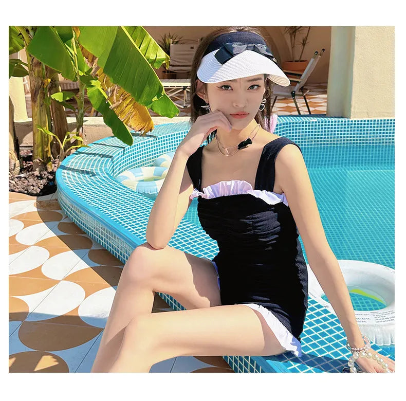 Women's solid colour one-piece jumpsuit swimsuit with suspender straps on a hanger.