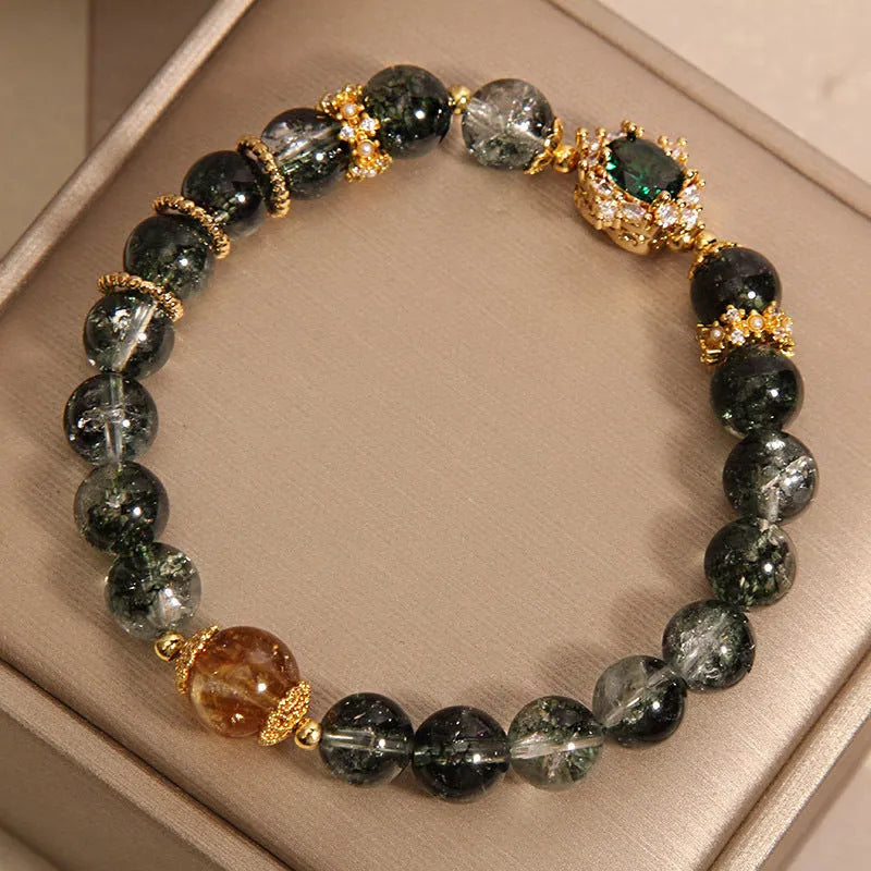 Women's green phantom quartz crystal bracelet with gold rutile needles, ruby quartz bead, pearls, and rhinestone details.