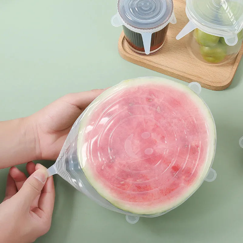 Set of six colourful silicone stretch lids in different sizes arranged on a kitchen counter.
