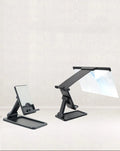 Black folding mobile phone screen amplifier with detachable holder on a desktop.