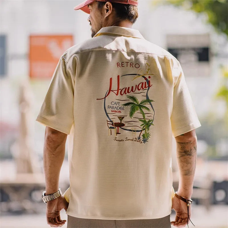 Light apricot men's shirt with bamboo and flower pattern, Cuban collar, on a hanger.