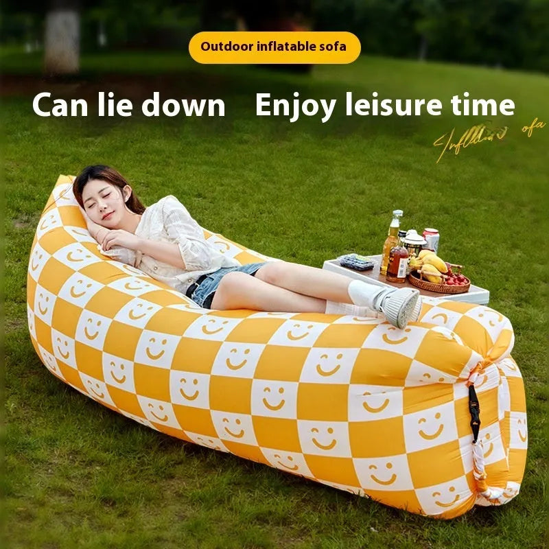 Yellow smiling face tip inflatable sofa inflated on green grass for camping