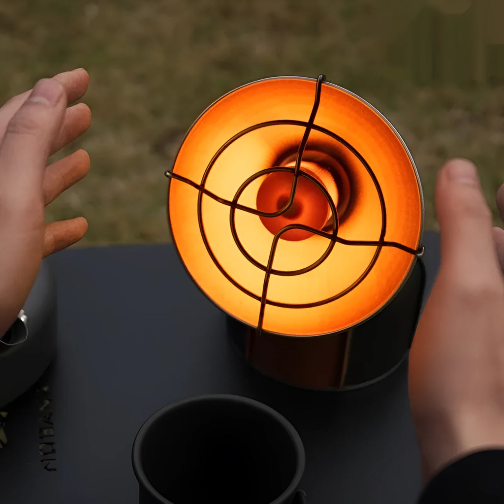 Black and orange portable outdoor heating stove with automatic ignition on a table.