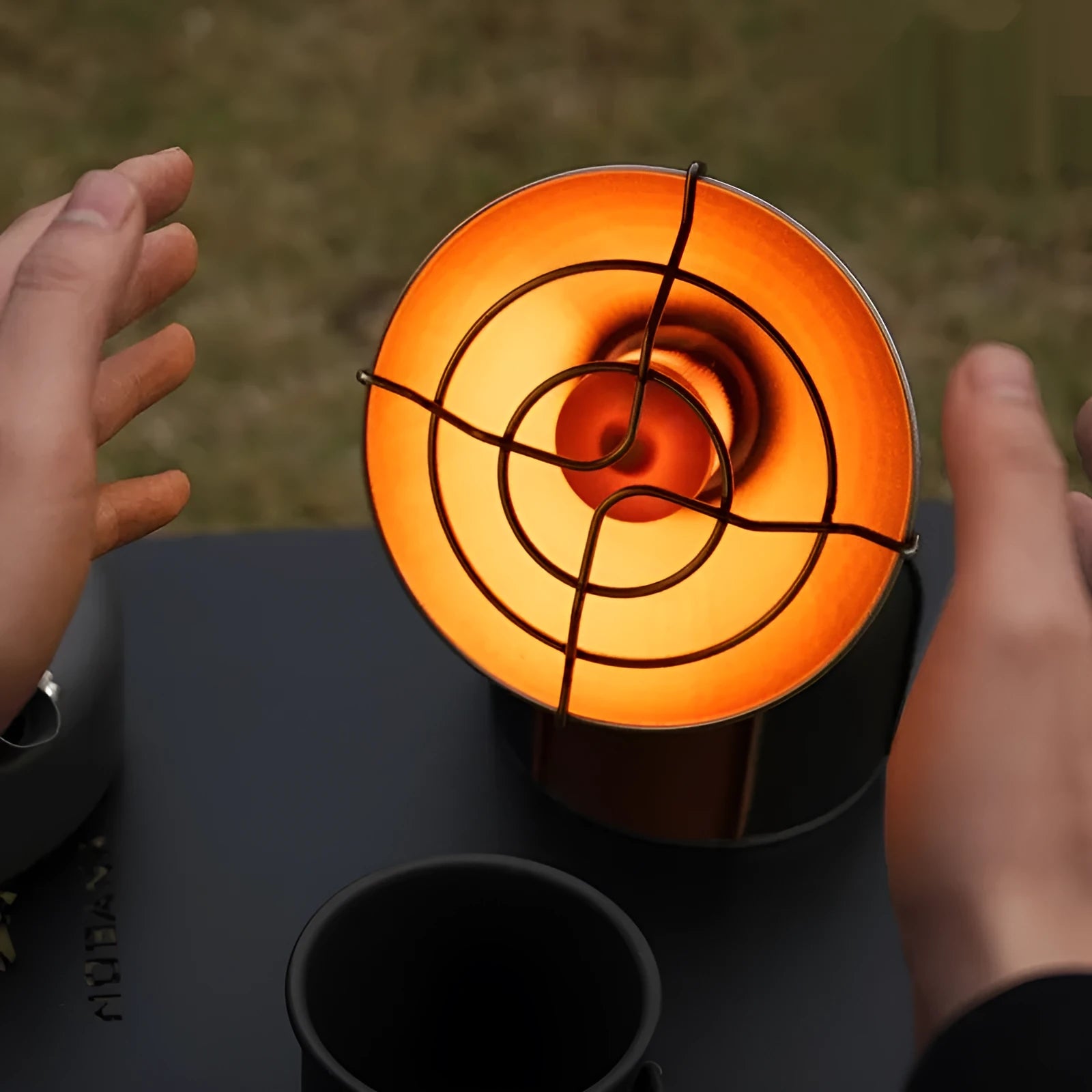 Black and orange portable outdoor heating stove with automatic ignition on a table.
