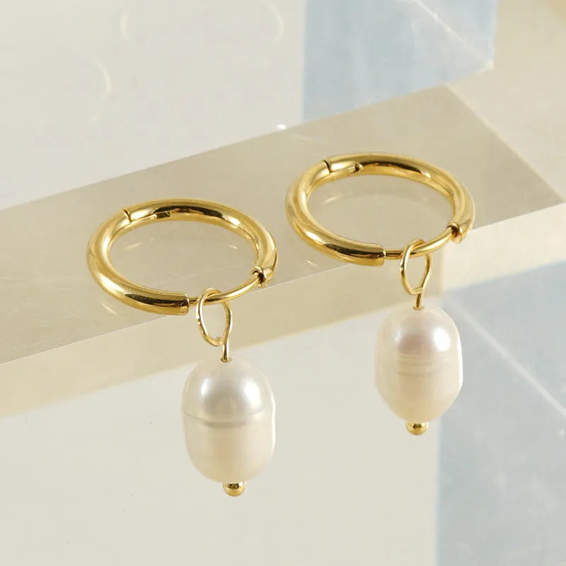 Gold geometric drop earrings with a freshwater pearl detail on a stainless steel setting.
