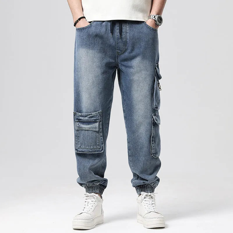 Man wearing loose-fit blue denim hip hop trousers with multiple pockets and a straight leg.