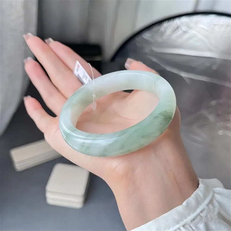 Tian Shan Cui jade bracelet with ice-like clarity and floating flower patterns on a wrist.