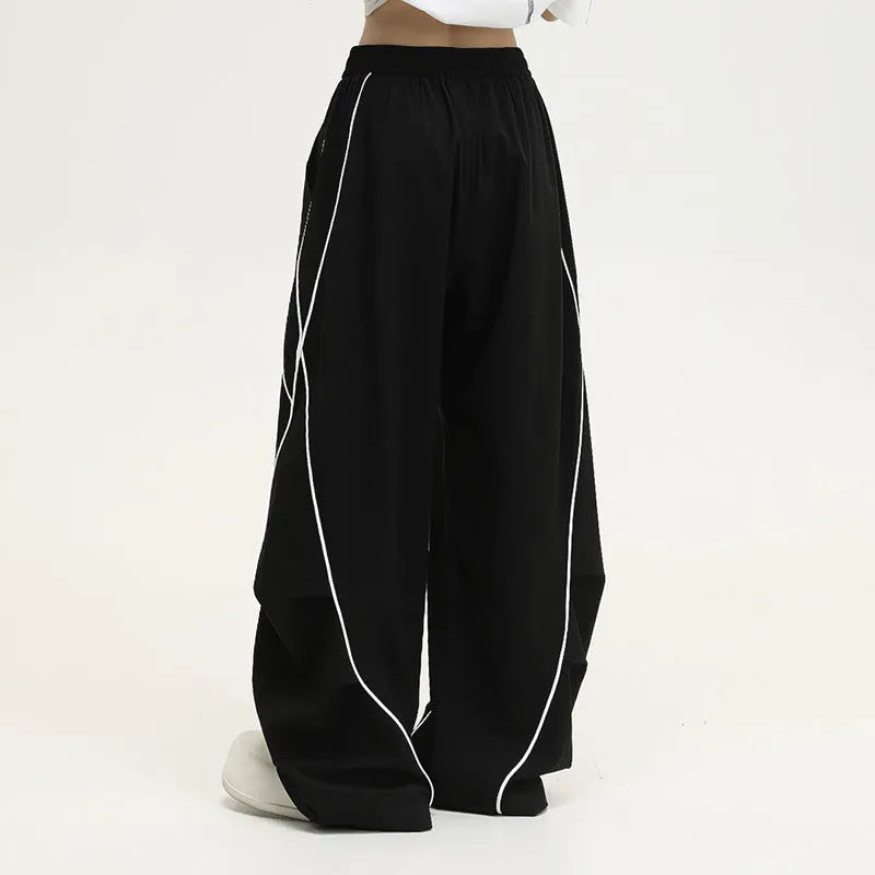 Black striped wide-leg pleated sports trousers showing loose fit and mid-waist design