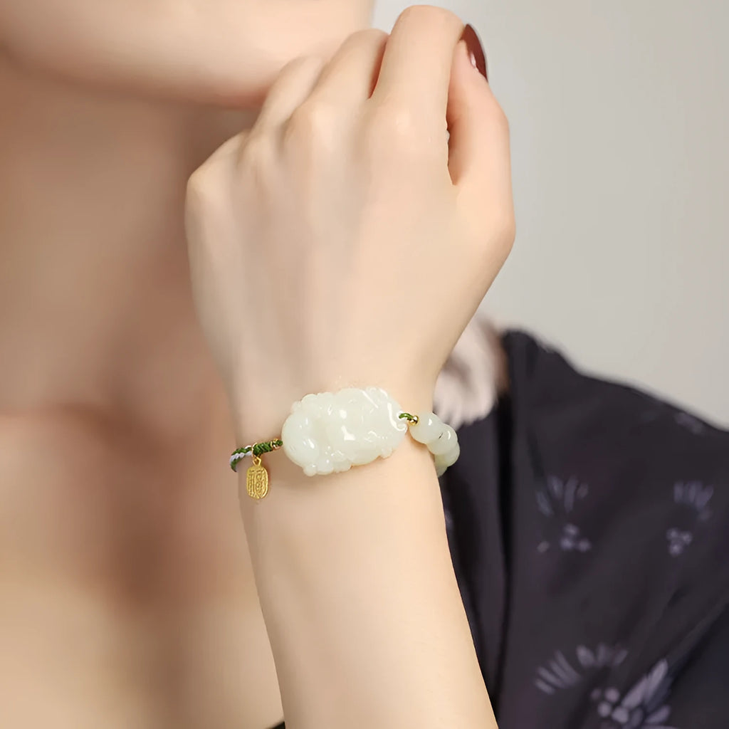 Hetian jade rabbit charm bracelet with sterling silver card on a white ice cotton rope.