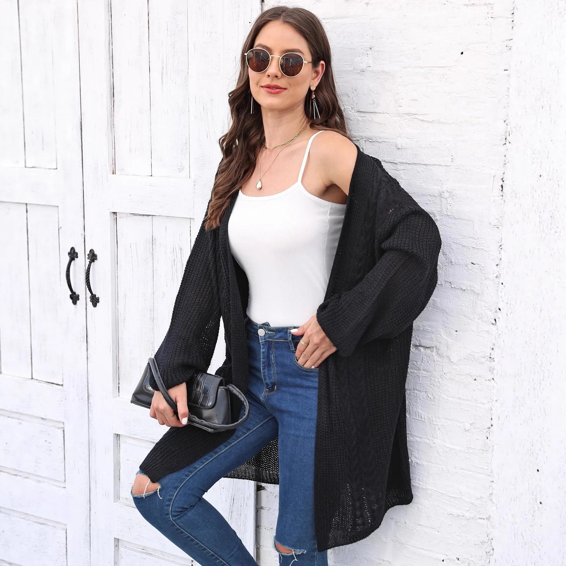 A women's loose-fitting solid colour acrylic sweater coat on a hanger.