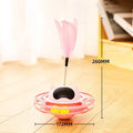 Pink cat tumbler turntable toy with a colourful baton on a flat surface.