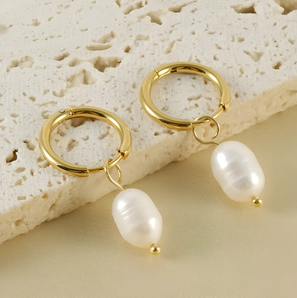 Gold geometric drop earrings with a freshwater pearl detail on a stainless steel setting.