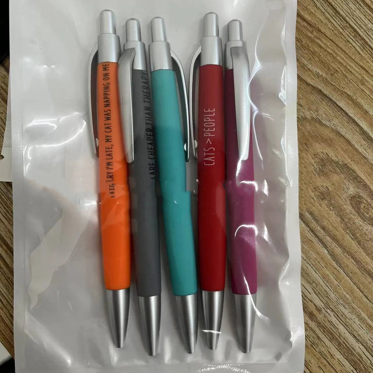 Set of five coloured push action automatic pens and a beaded storage bag