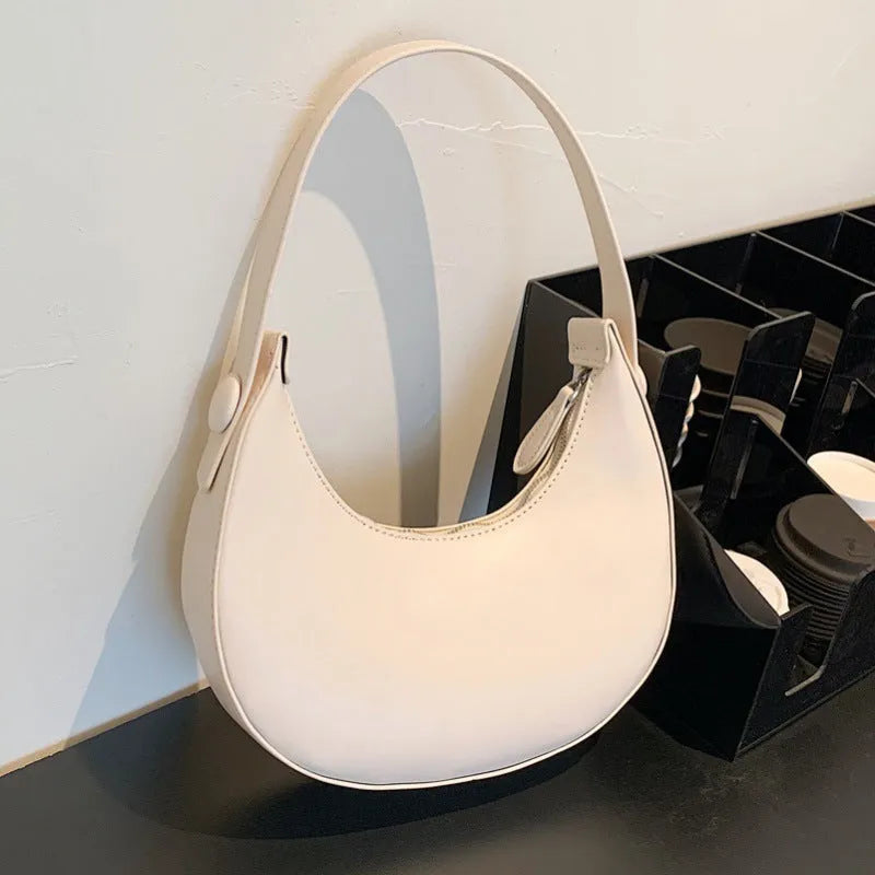 Women's retro dumpling-shaped shoulder bag in PU, shown in one of four colours, featuring an outer pocket and internal zipper compartment.