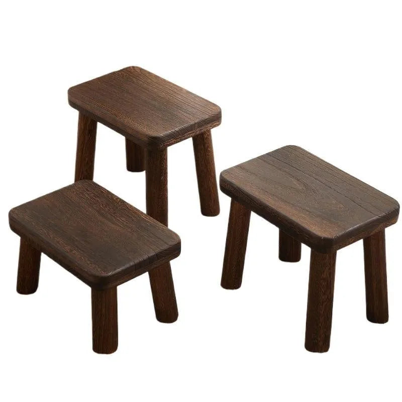 Distressed solid wood shoe stool with bracket legs in a living room setting.