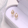 A pair of geometric shaped silver ear studs with sweet white crystal centres on a plain background.