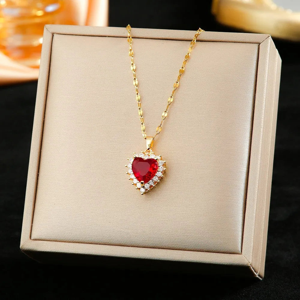 Gold-red titanium steel necklace with heart and flower pendant, matching ear studs, and ring on a white background.